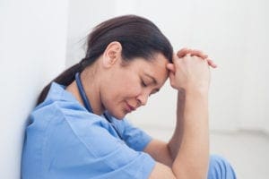 Upset nurse sitting on the floor in hospital ward